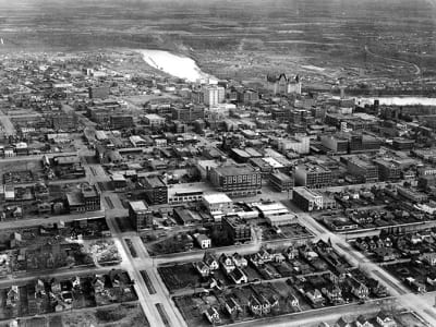 Aerial view of downtown Edmonton with streets, low-rise buildings, and the river valley in the distance.